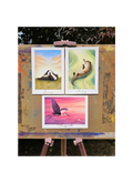 Three colorful paintings on a wooden easel outdoors.