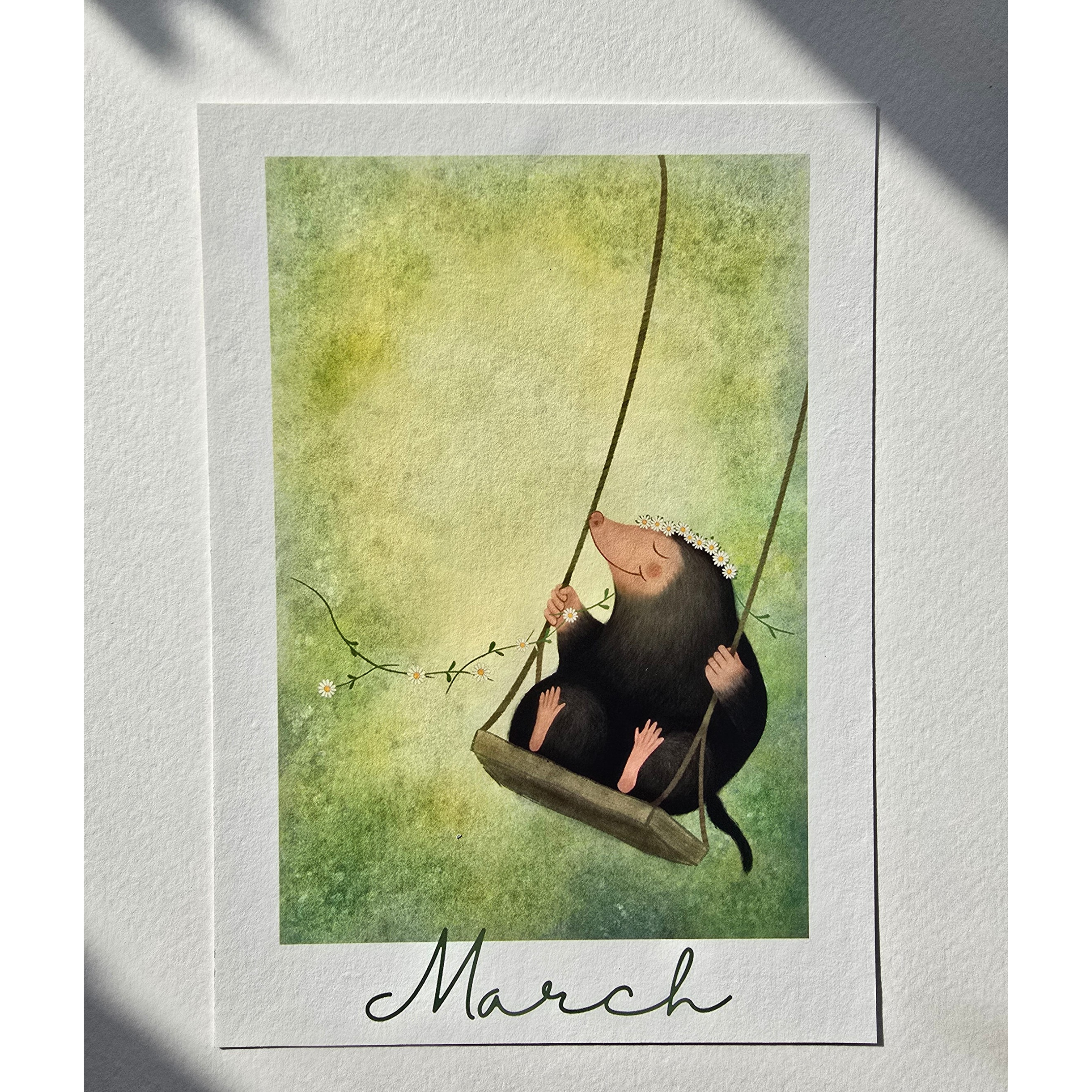 Illustration of a mole on a swing with 'March' text, framed against a textured white background.